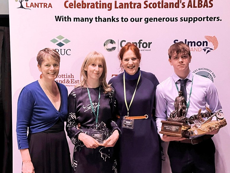 Four people pose for a photo with their trophies.